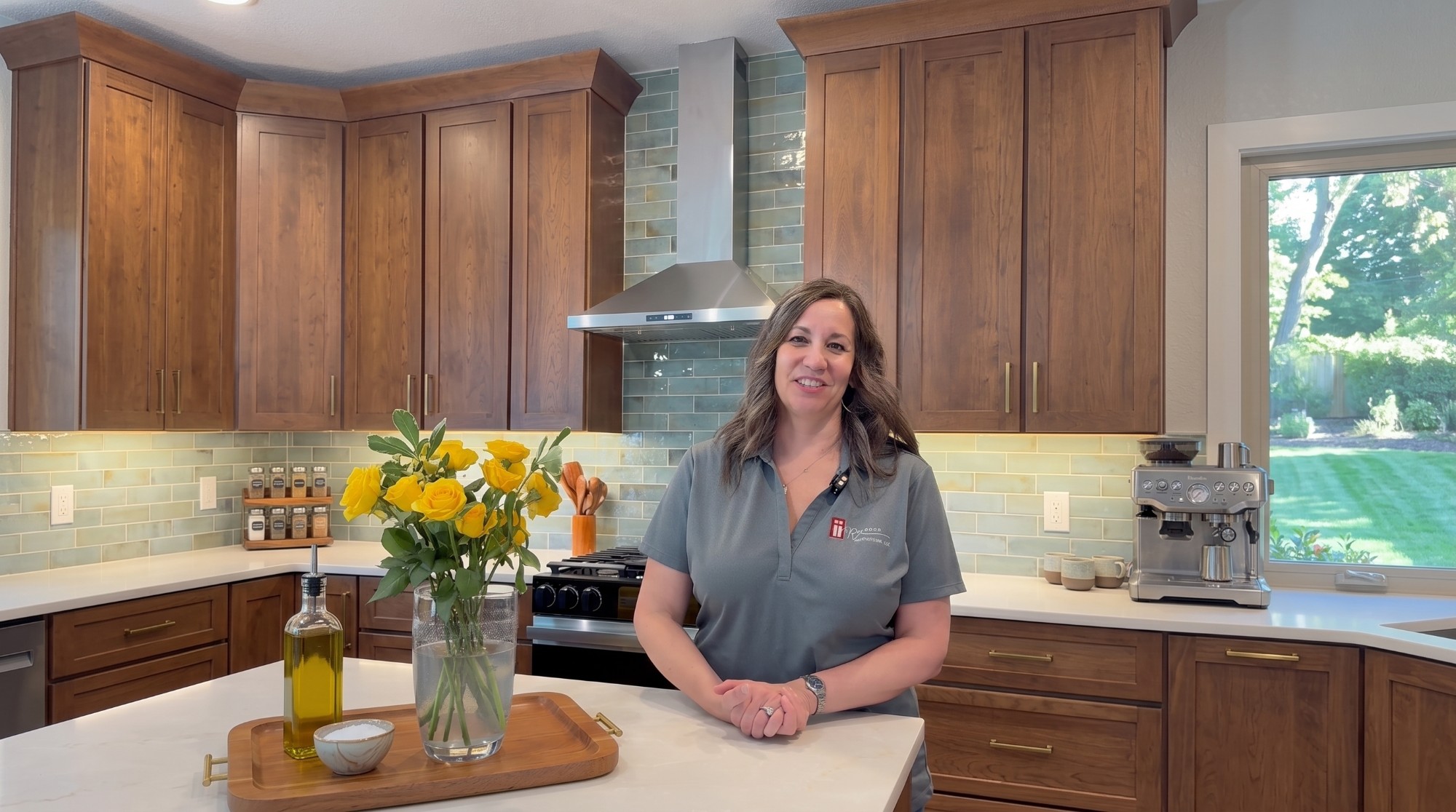 Tracy Stegner of Red Door Renovations in a finished kitchen with walnut cabinetry, quartz counters and a green tile backsplash
