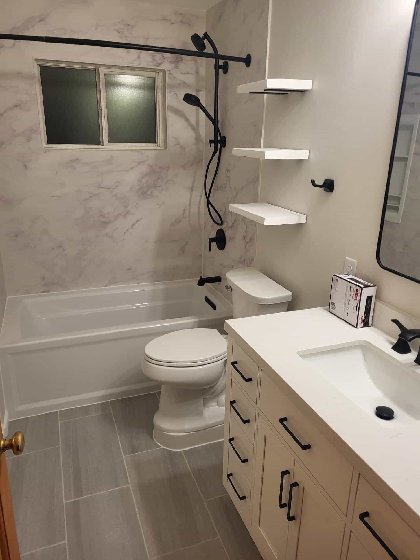 Marble-look tub surround with black fixtures and floating shelves