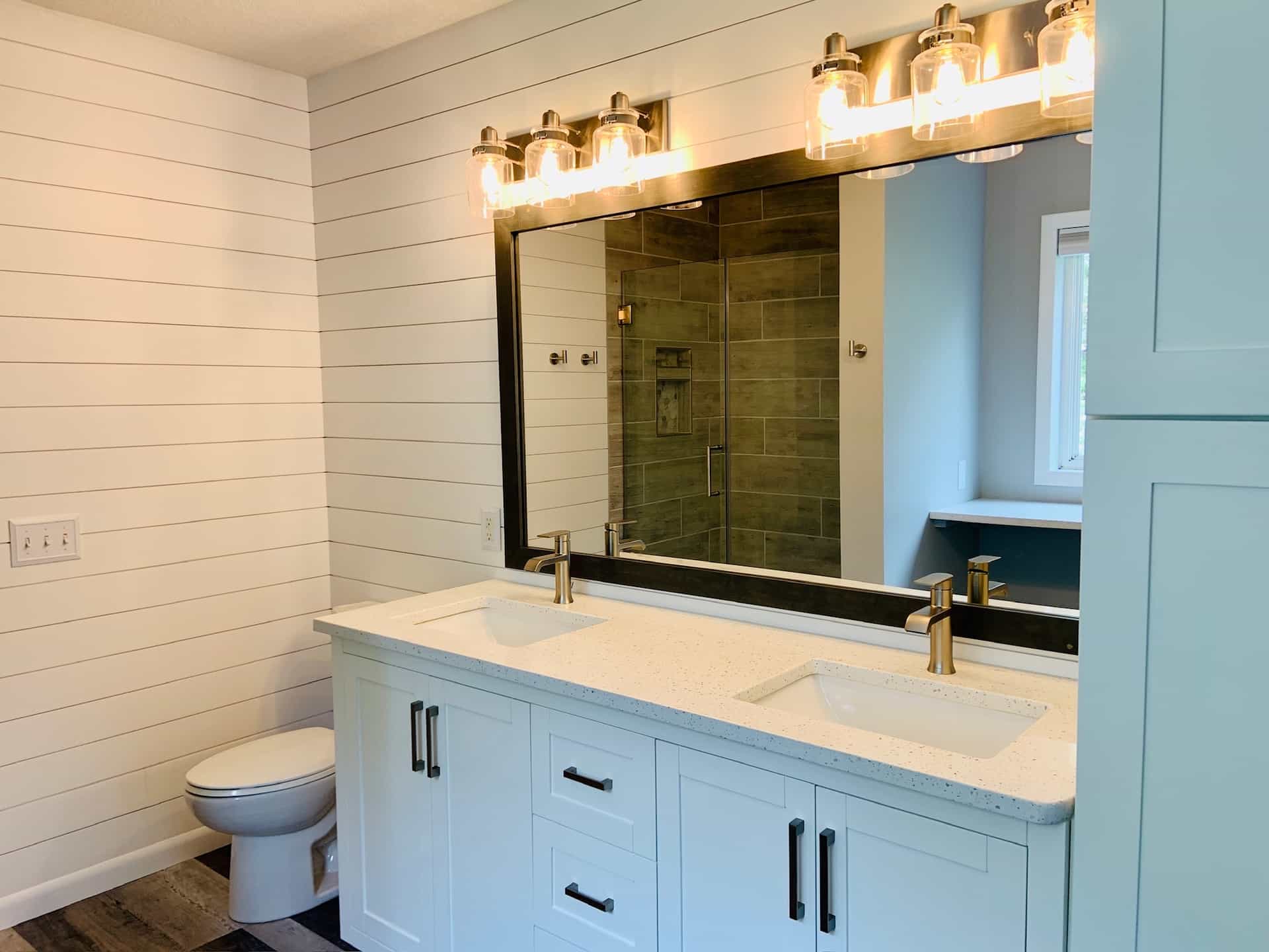 Shiplap bathroom with a double vanity and a framed mirror